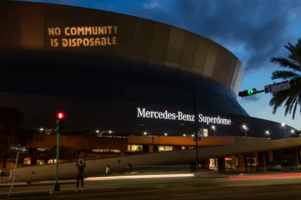 “No Community Is Disposable,” Activist Welcome Break Free from Plastic Pollution Act with Projections on Superdome